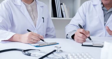 Nucala | ANCA Vasculitis News | Treatments | Two people in lab coats write on clipboards in office setting