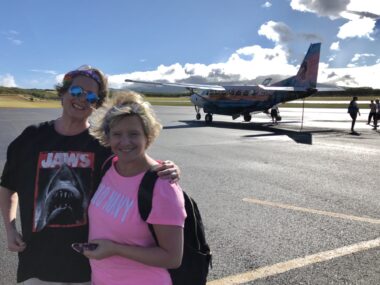 Pam Squires, left, and Sarah Jones stand in front of an airplane on a runway.